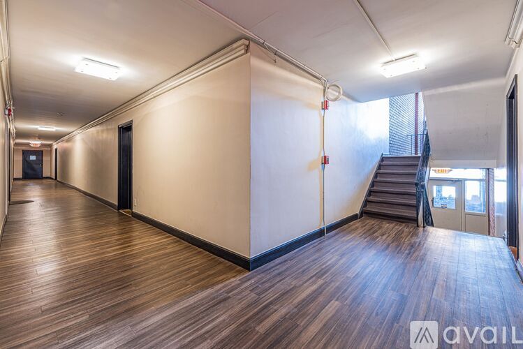 A long hallway with wooden floors and a staircase on the right side.
