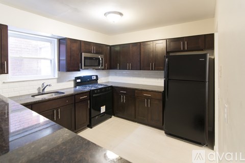 A kitchen with black appliances and brown cabinets.