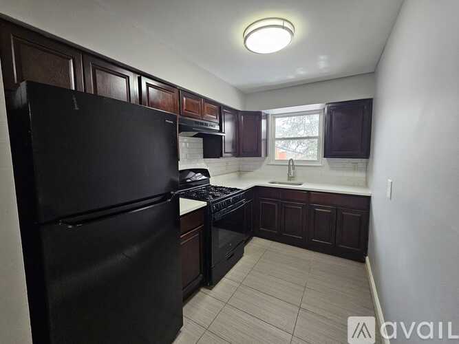 A kitchen with black appliances and brown cabinets.