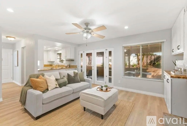 A modern living room with a grey couch and a ceiling fan.