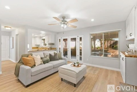 A modern living room with a grey couch and a ceiling fan.