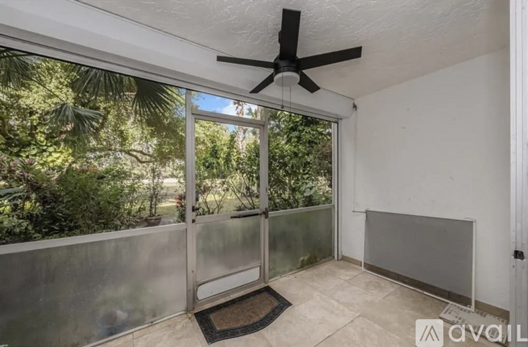 A room with a ceiling fan and sliding glass doors leading to a lush green outdoor area.
