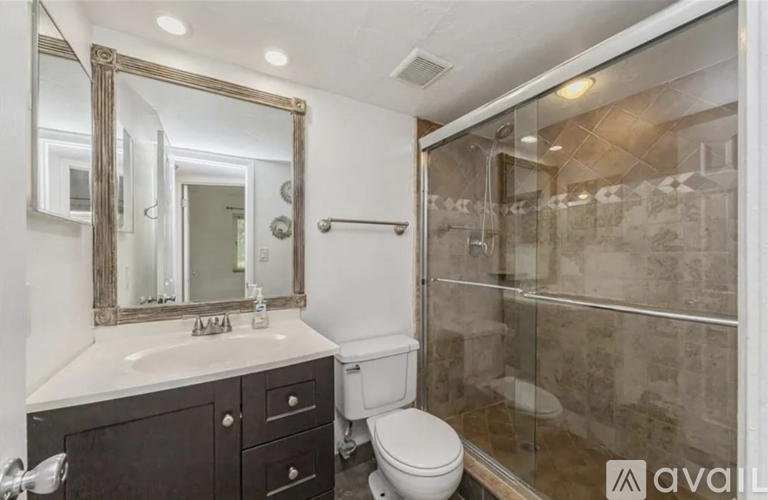 A bathroom with a toilet, sink, and mirror.