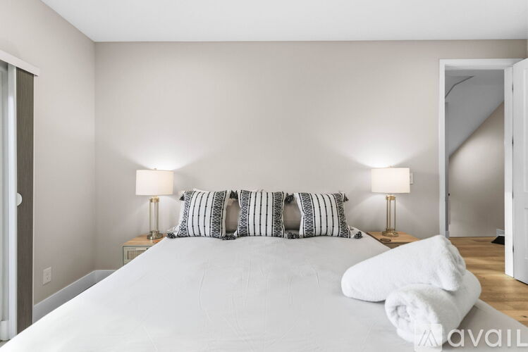 A bedroom with a large bed and two lamps.
