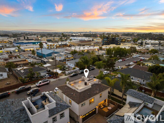 A sunset view of a neighborhood with a house in the foreground and a swimming pool.