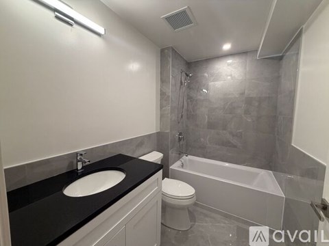 A bathroom with a black countertop and a white sink.