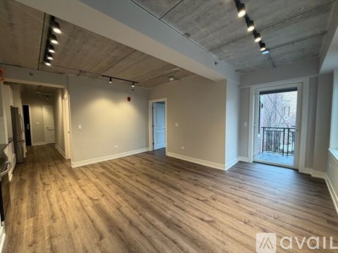 A spacious room with wooden flooring and a balcony with a railing.
