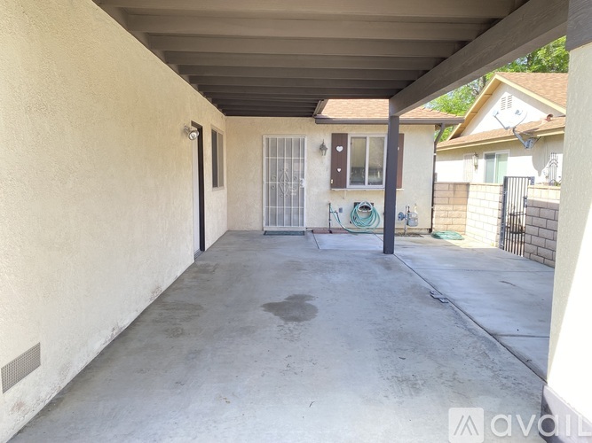 A patio area with a concrete floor and a white wall.