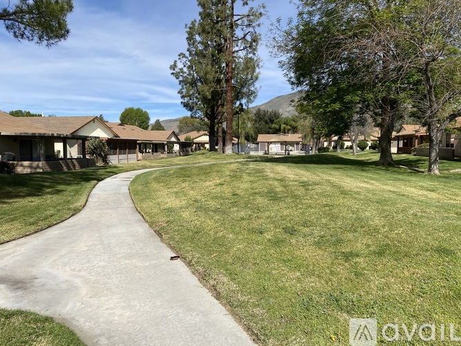 A grassy area with a pathway and houses in the background.