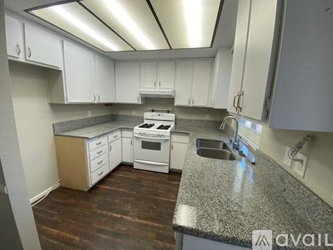 A kitchen with white cabinets and a granite countertop.
