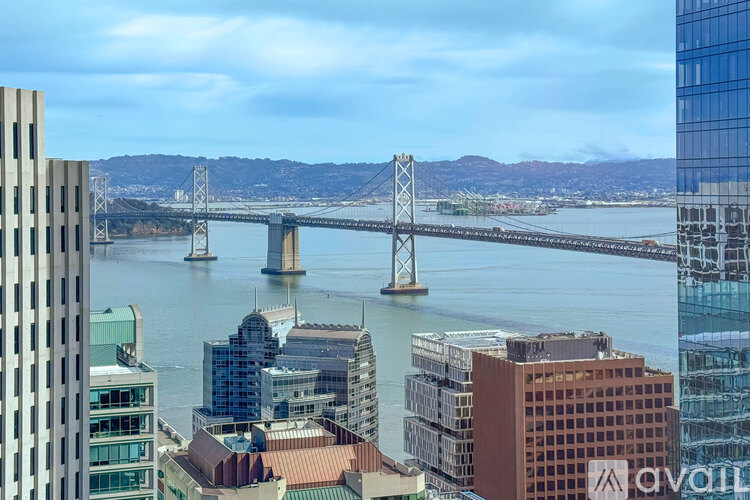 A cityscape with a bridge in the background and a building with the word "AVAIL" on it in the foreground.