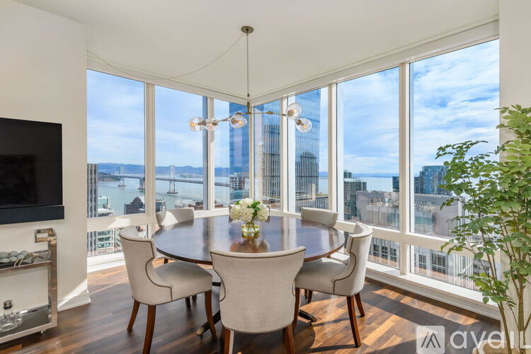 A dining room with a table and chairs with a view of the city.