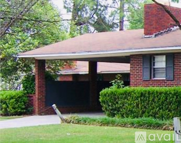 A house with a red roof and a green lawn in front.