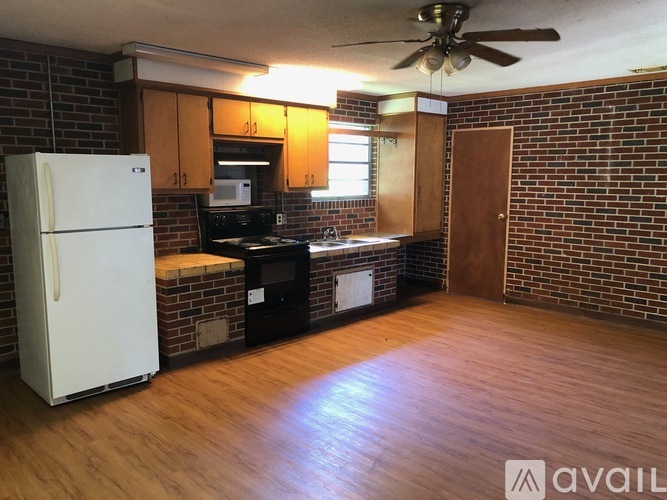 A kitchen with a white refrigerator and a brick wall.