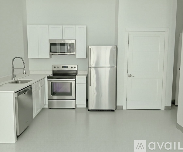 A kitchen with a refrigerator, oven, microwave, and sink.
