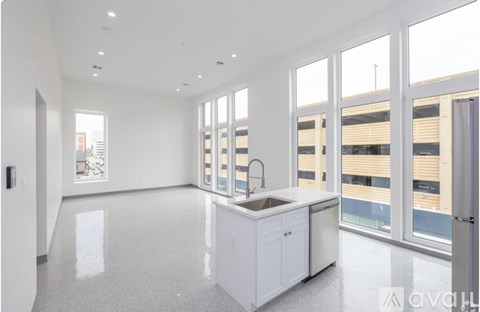 A modern living room with a grey sofa, a wooden coffee table, and a bed with white bedding.
