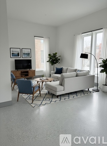 A living room with a white sofa, a blue chair, a wooden table, and a television.