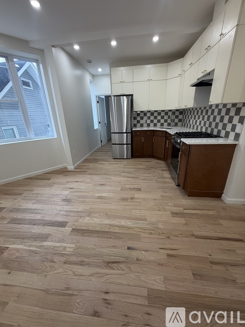 A kitchen with wooden flooring and a checkered backsplash.