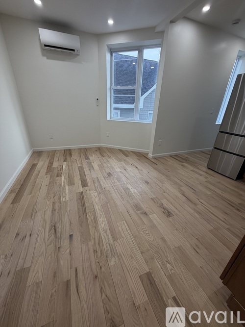 A room with wooden flooring and a window.