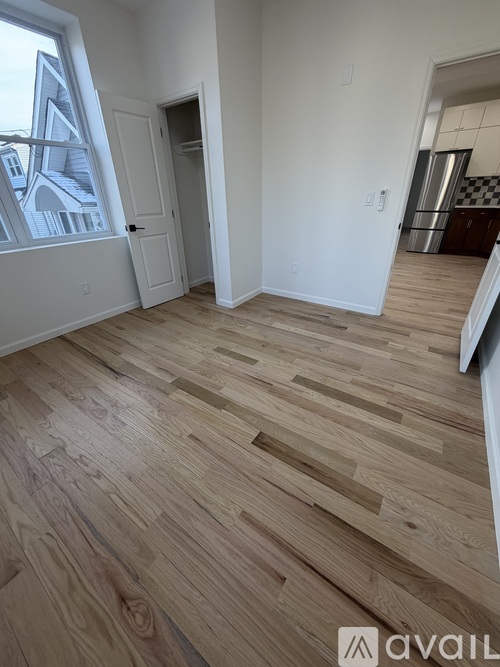 A room with wooden flooring and a window showing a building outside.