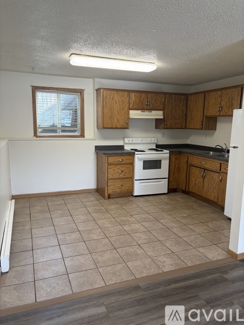 A kitchen with a white stove top oven and wooden cabinets.
