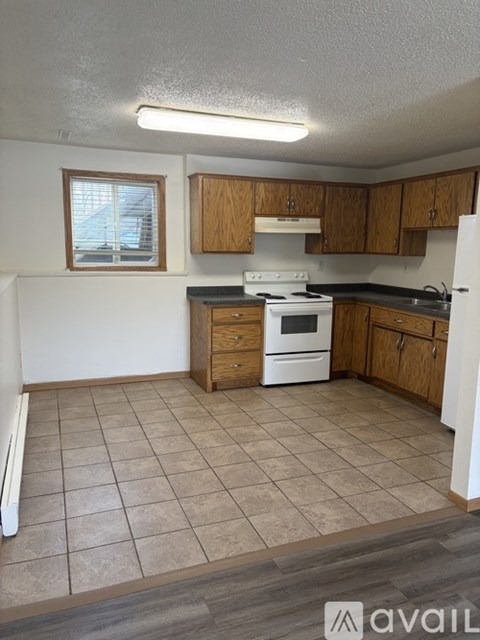 A kitchen with a white stove top oven and wooden cabinets.