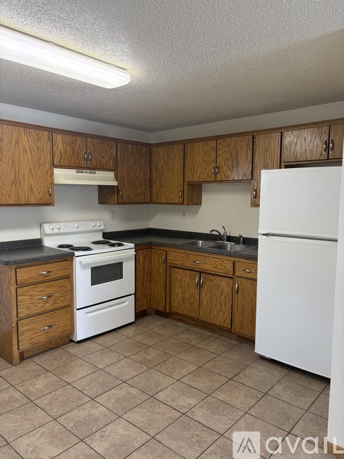 A kitchen with white appliances and wooden cabinets.