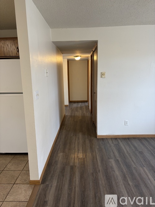 A hallway with a white door and a white wall.
