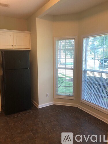 A black refrigerator sits in a kitchen next to a window.