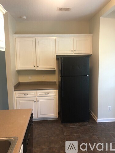 A kitchen with white cabinets and a black refrigerator.