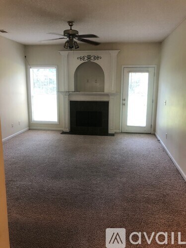 A living room with a fireplace and a ceiling fan.