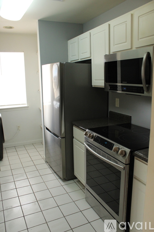A kitchen with a black fridge and stove top oven.