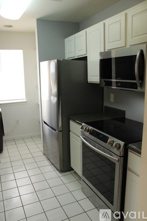 A kitchen with a black fridge and stove top oven.