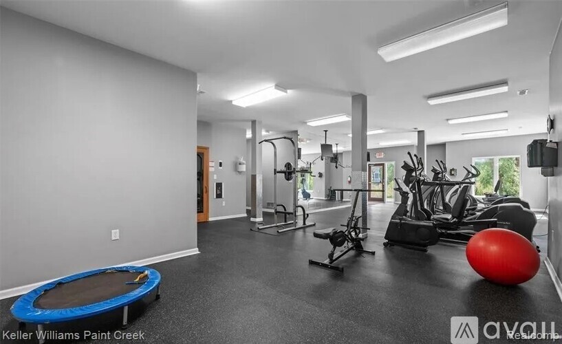 A spacious gym with a variety of equipment including a treadmill, exercise bike, and a trampoline.