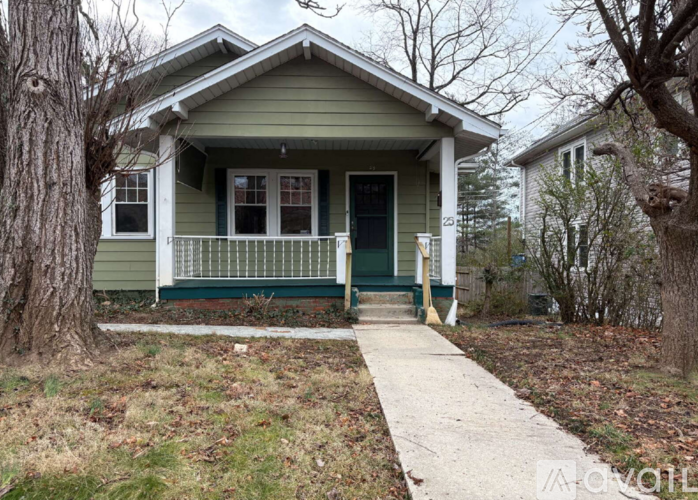 A green house with a porch and a white door.