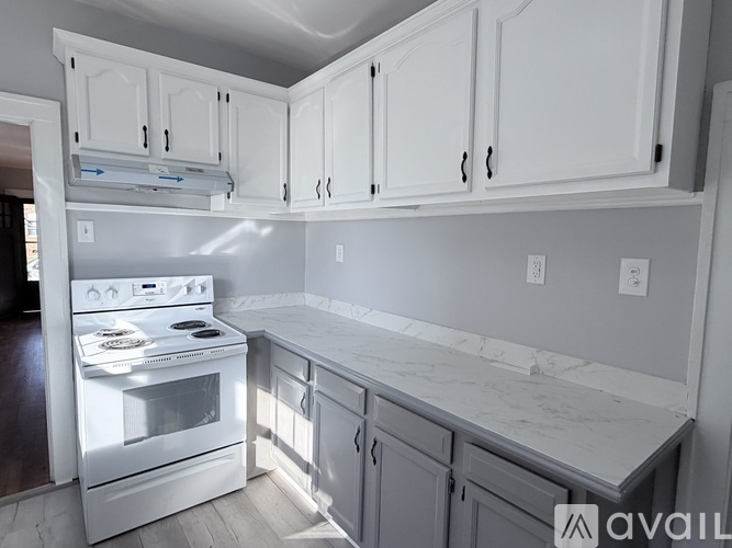 A kitchen with a white refrigerator and a window with blinds.