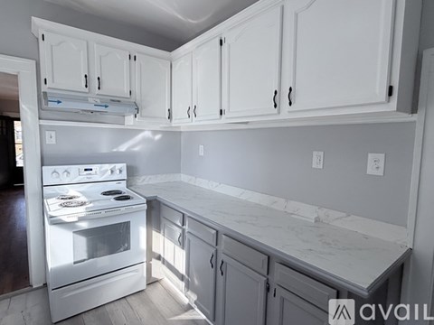 A kitchen with a white refrigerator and a window with blinds.
