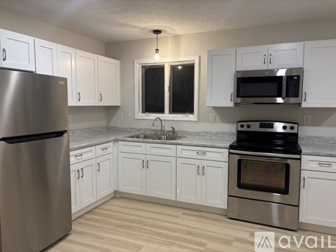 A kitchen with white cabinets and a stainless steel refrigerator.