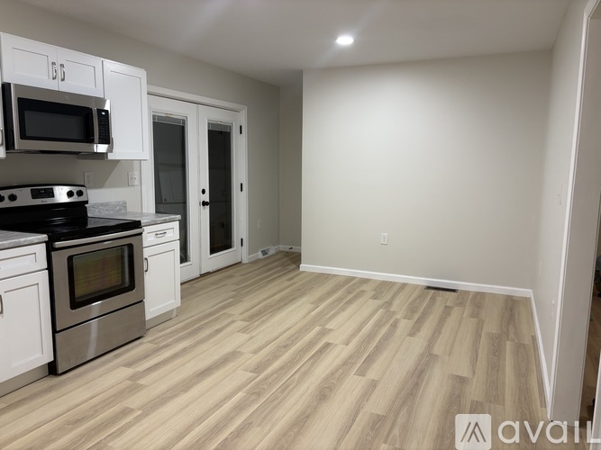 A kitchen with white cabinets and a wooden floor.