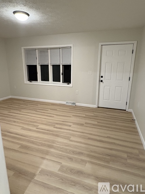 A room with a white door and a window with blinds.