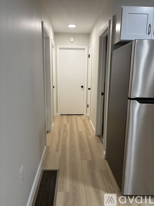 A long hallway with a refrigerator on the right side.