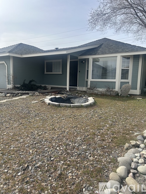 A house with a grey roof and a stone wall in front.