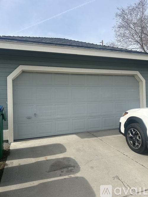 A white car is parked in front of a light blue garage door.