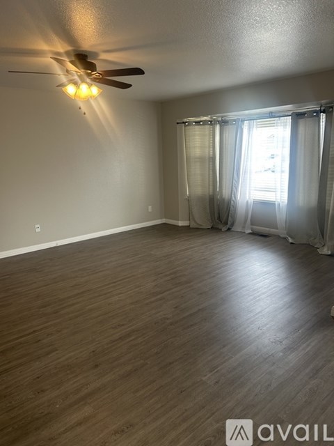A room with a ceiling fan and a window with curtains.