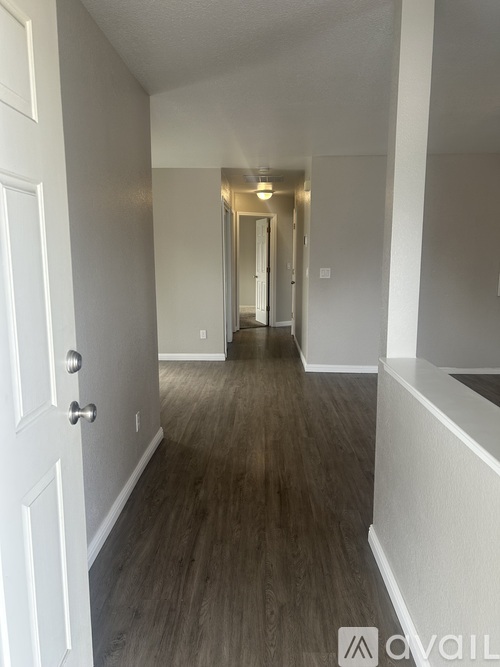 A hallway with wood flooring and white walls.