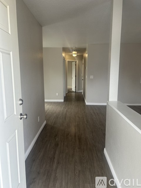 A hallway with wood flooring and white walls.