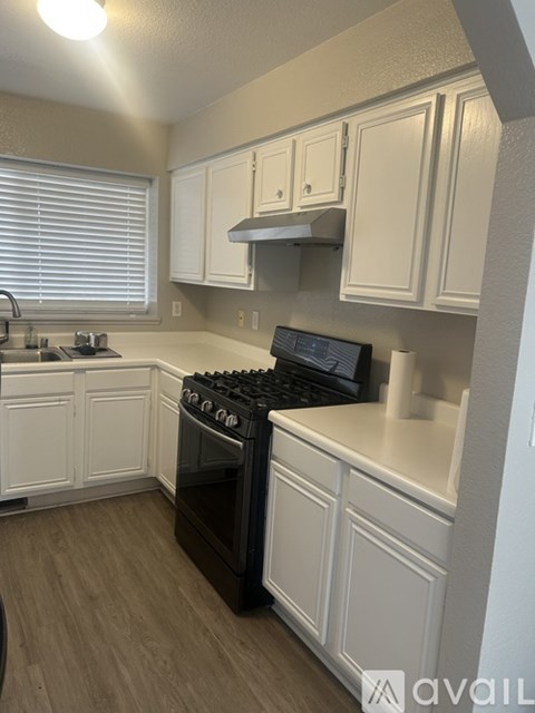 A kitchen with white cabinets and a black stove top oven.