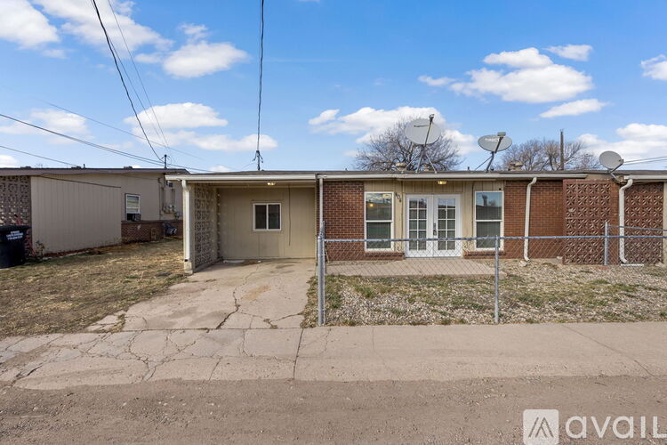 A small house with a fence and a satellite dish on the roof.