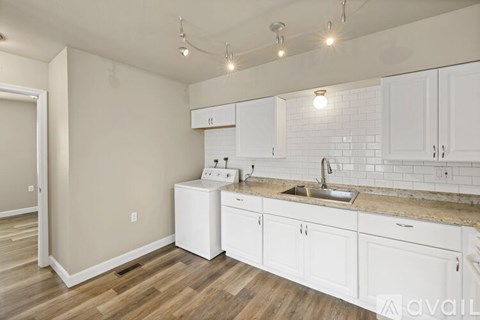 A kitchen with white cabinets and a wooden floor.