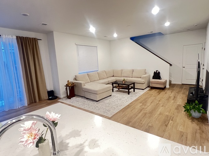 A living room with a white sofa set and a wooden floor.